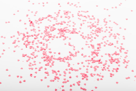 Many pink sugar hearts are scattered on a light background.の写真素材