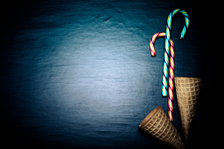 Candy sticks and waffle cones for ice cream on a black background. Space for text. Toned.の写真素材