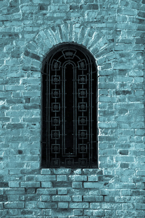 Wall of red bricks with window. Toned blue.の写真素材