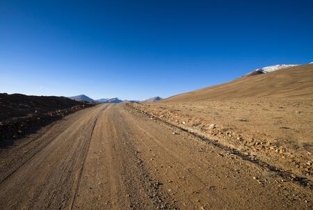 Beautiful landscape - country road in desert valley. The rocky mountains and blue sky are behind. Toned.の写真素材