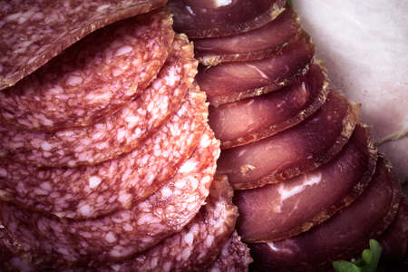 Slices of different types of sausages and salad leaf. Toned.の写真素材