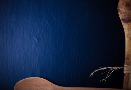 Two wooden spoons on the edges of the black background. Space for text. Toned.の写真素材