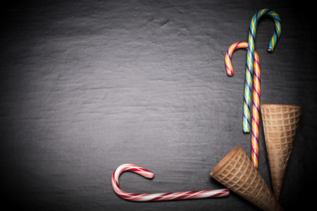 Candy sticks and waffle cones for ice cream on a black background. Space for text. Toned.の写真素材