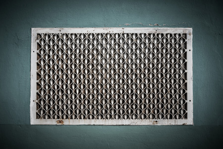 Old metal patterned ventilation grid on the plastered wall. Toned.の写真素材