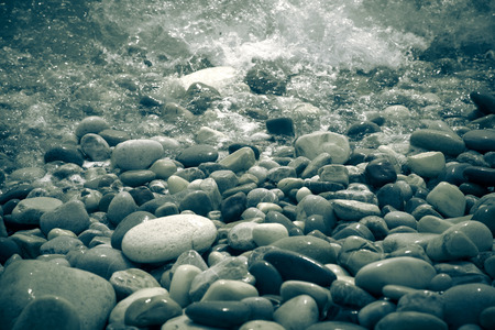 Wave is transformed into foam on a pebble beach in Cyprus. Shallow depth of field.の写真素材