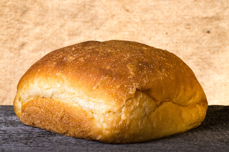 Loaf of white wheat bread on old wooden table.