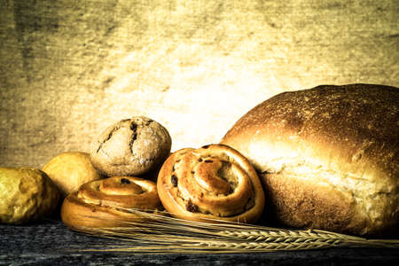 Bread assortment and wheat ears on an old wooden table. Toned.の写真素材
