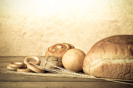 Bread assortment and wheat ears on an old wooden table. Toned.