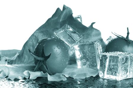 Cherry tomatoes and green salad with ice cubes on a black table on a white background. Selective focus. Toned.の写真素材