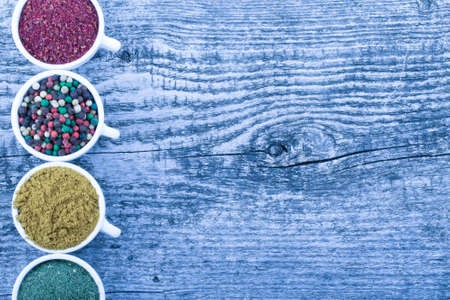 White ceramic cups with different kinds of spices on old wooden board. Selective focus. Toned.の写真素材