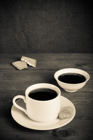 Cup of tea with jam, biscuits and marmalade on old wooden table against the background of burlap. Toned.の写真素材
