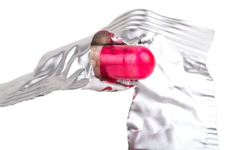 Medicine capsule in torn packaging isolated on white background.の写真素材