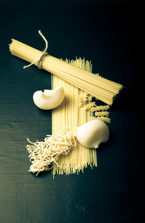 Different kinds of pasta on a black background. Toned.の写真素材