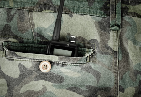 Portable radio in a pocket of pants with camouflage pattern. Toned.の写真素材