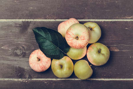 Yellow-red seasonal apples with leaf on the background of old boards. Toned.の写真素材
