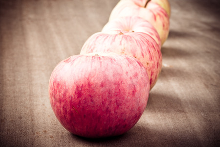 Row of yellow-red seasonal apples on the background of old boards. Closeup. Toned.の写真素材