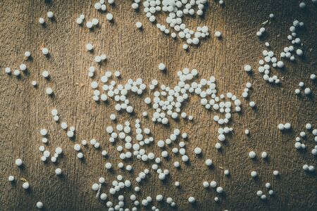 Pieces of foam plastic like snow balls on the background of the old wooden board table. Closeup. Toned.の写真素材