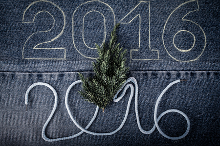 Fresh branch of christmas tree and the numbers 2016 of rope and chalk contour on the background of the jeans. Christmas theme. Toned.の写真素材