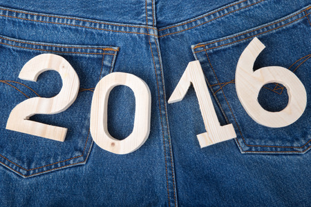 Light wooden figures 2016 on the background of the back of the jeans. Christmas theme.