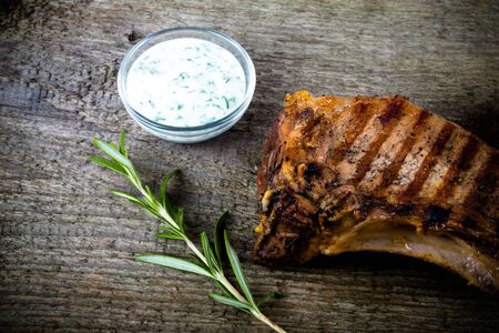 Hot grilled meat with vegetables and creamy souse on old grey wooden board for background.の写真素材