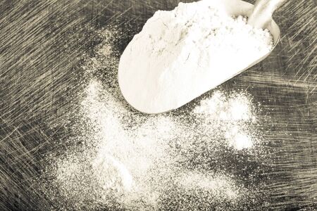 Scoop with white wheat flour on an old rugged cutting board. Toned.の写真素材