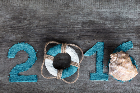 Figures 2016 on old grey wooden background in sea style with wood, denim and rope material.