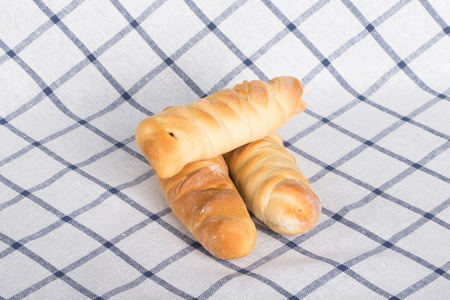 Fresh baked sausages buns on checkered tablecloth