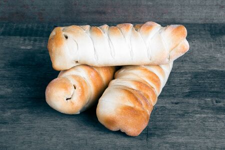 Fresh baked sausages buns on old grey wooden table like background.