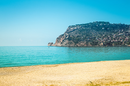 Stony beach and beautifull view to ancient fortress on the Alanya peninsula Turkey. Toned.の写真素材