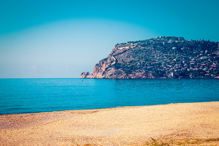 Stony beach and beautifull view to ancient fortress on the Alanya peninsula Turkey. Toned.の写真素材