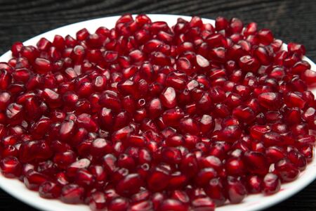 Juicy ripe pomegranate fruit on a black wooden table for background. Selective focus.の写真素材