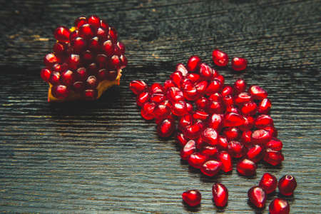 Juicy ripe pomegranate fruit on a black wooden table for background. Selective focus. Toned.の写真素材