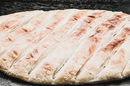 Turkish bread Katmer on a black wooden table or board. Selective focus. Shallow depth of field....