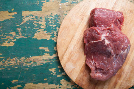 Fresh raw meat on light cutting board on an old wooden table. Ingredients for traditional turkish meal - Kuru fasulye.の写真素材