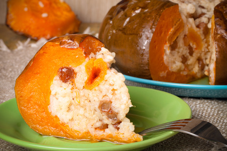 Rice porridge with dried fruits and spices in a pumpkin on a plate. Toned.の写真素材