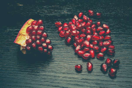 Juicy ripe pomegranate fruit on a black wooden table for background. Selective focus. Toned.の写真素材