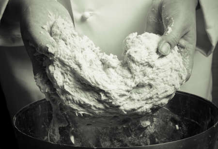 Woman's hands knead dough. Selective focus. Toned.の写真素材