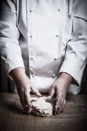 Woman's hands knead dough. Selective focus. Toned.の写真素材