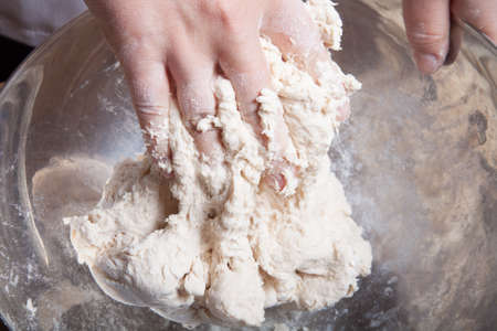 Woman's hands knead dough. Selective focus.の写真素材