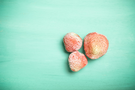 Frozen strawberries on a blue wooden cutting board. Selective focus. Toned.の写真素材