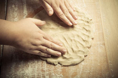 Woman's hands in process of preparing of dough for gingerbread cookie. Toned.