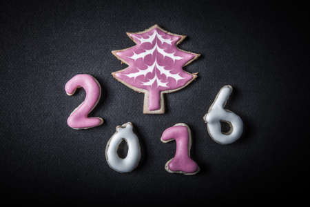 Gingerbread homemade cookies with icing on a black table or board for background. Figures 2016 New...