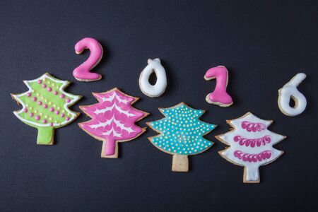 Gingerbread homemade cookies with icing on a black table or board for background. Figures 2016 New...