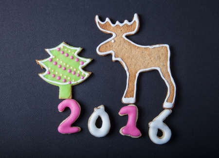 Gingerbread homemade cookies with icing on a black table or board for background. Figures 2016 New year theme.の写真素材