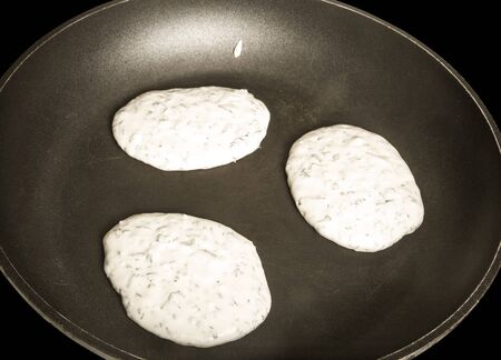 Raw pancakes with herbs on a pan. Toned.