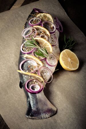 Fish Nelma with lemon, onion and rosemary on a wooden table. Toned.の写真素材