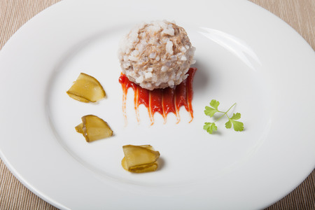 Cutlet with rice, slices of pickle and ketchup on white plate on grey napkin.の写真素材