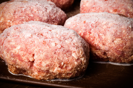 Frozen cutlets on a brown cutting board. Selective focus. Toned.