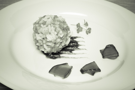 Cutlet with rice, slices of pickle and ketchup on white plate on grey napkin. Toned.
