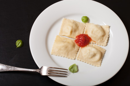 Russian ravioli - pelmeni with tomato souce and basil on a white plate. Selective focus.の写真素材